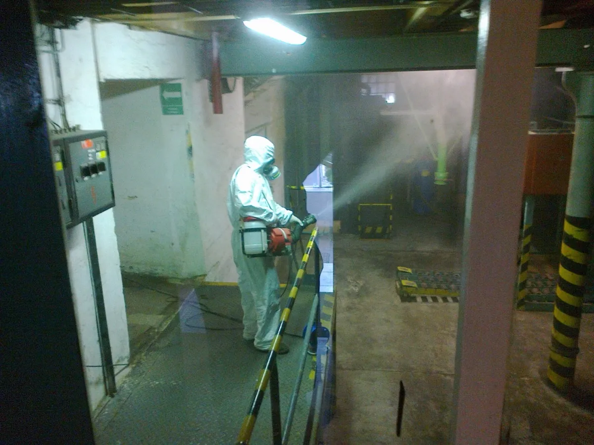 Fumigace — technik v ochranném obleku s respirátorem aplikuje plyn